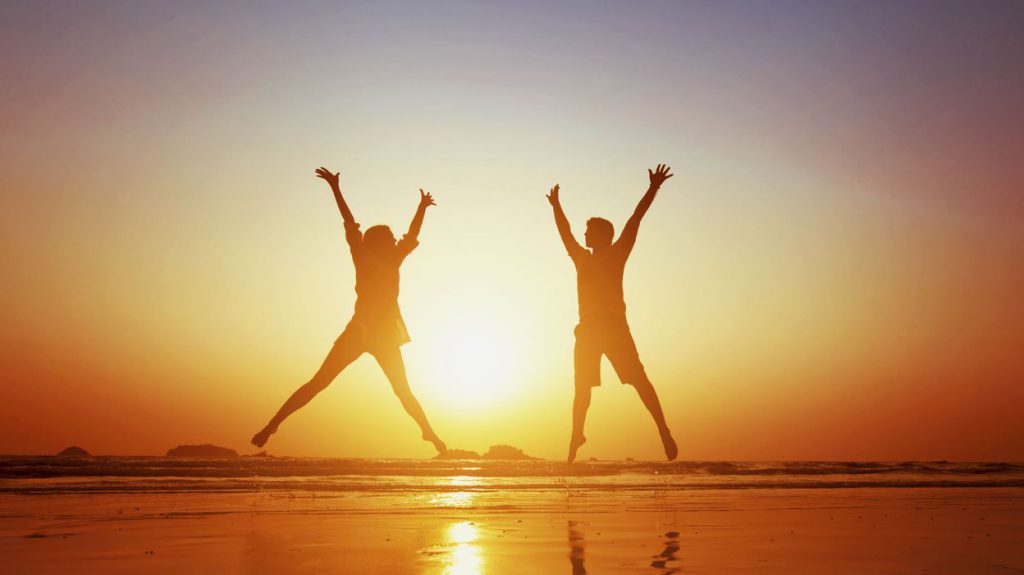 Deux adultes qui sautent et lèvent les bras devant le soleil. Cela représente le fait de se contacter